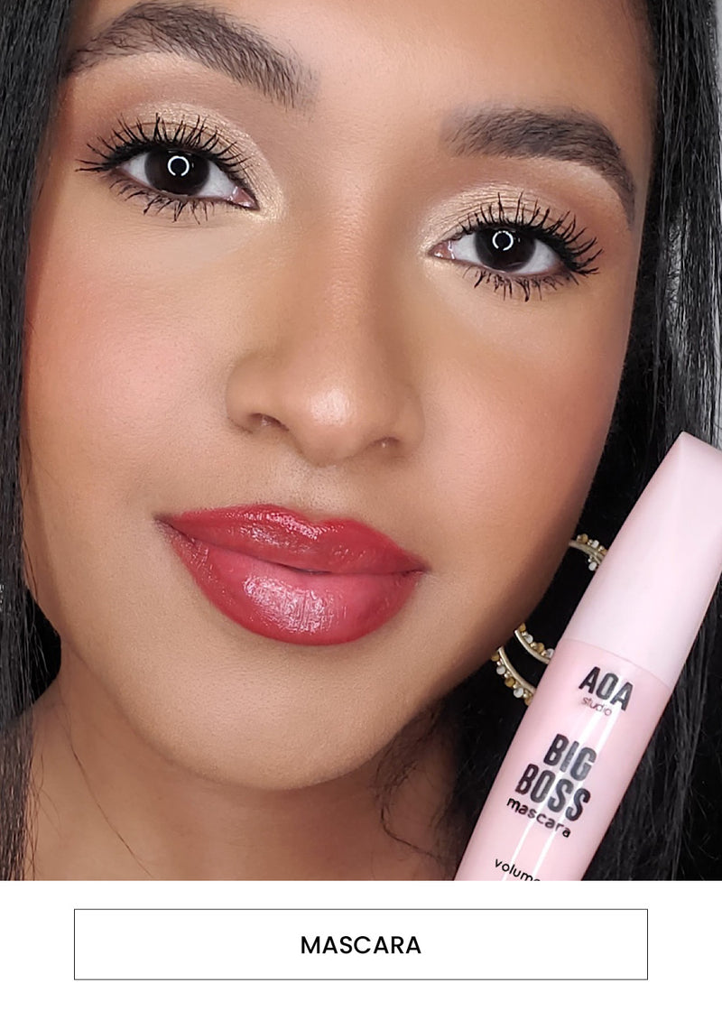 Image of a woman wearing and holding the Big Boss Mascara alongside a  “Mascara” button