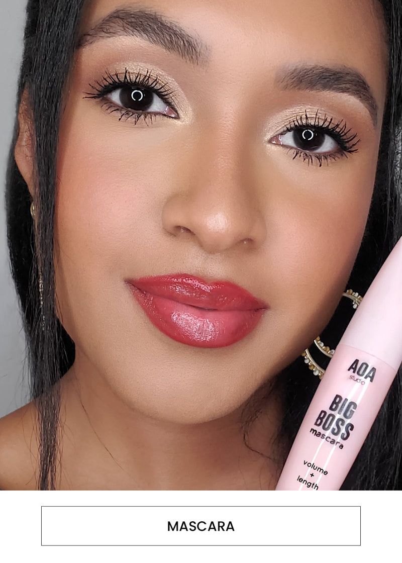 Image of a woman wearing and holding the AOA Big Boss Mascara in black alongside a “Mascara” button