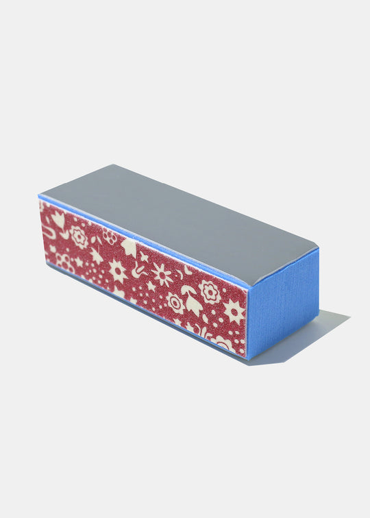 A blue, grey, and red nail buffer block with a floral pattern on one side
